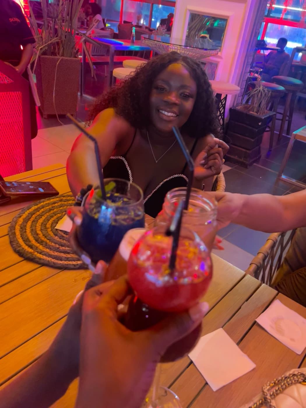 Friends raising colorful drinks during a Nairobi night out
